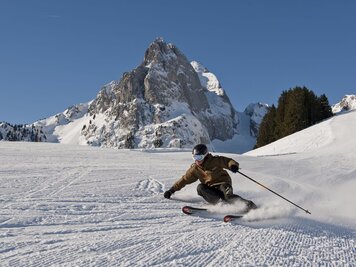 Skifahrer auf frisch gespurter Piste, im Hintergrund die Gummfluh